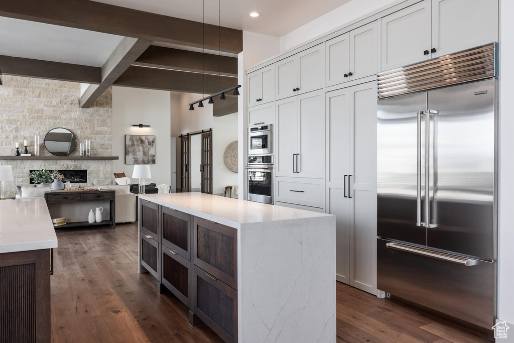 Kitchen featuring dark hardwood / wood-style floors, appliances with stainless steel finishes, a center island, and pendant lighting