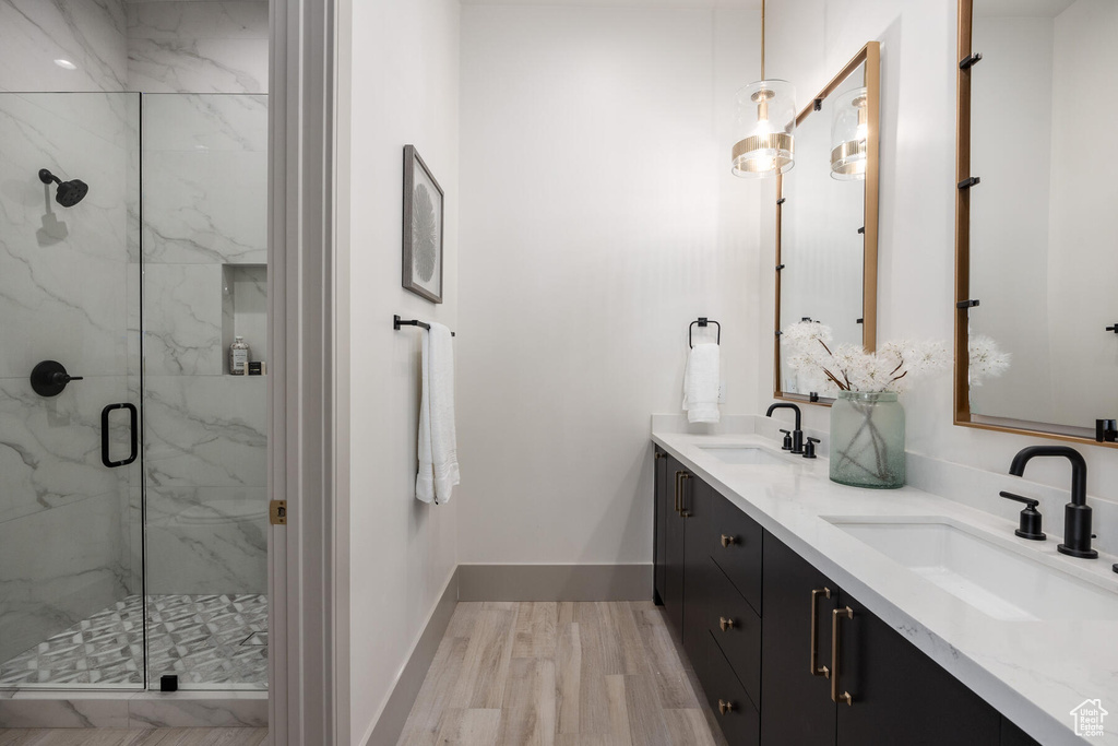 Bathroom featuring hardwood / wood-style flooring, dual vanity, and walk in shower