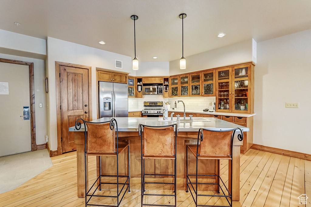 Kitchen featuring a center island with sink, light hardwood / wood-style floors, and stainless steel appliances