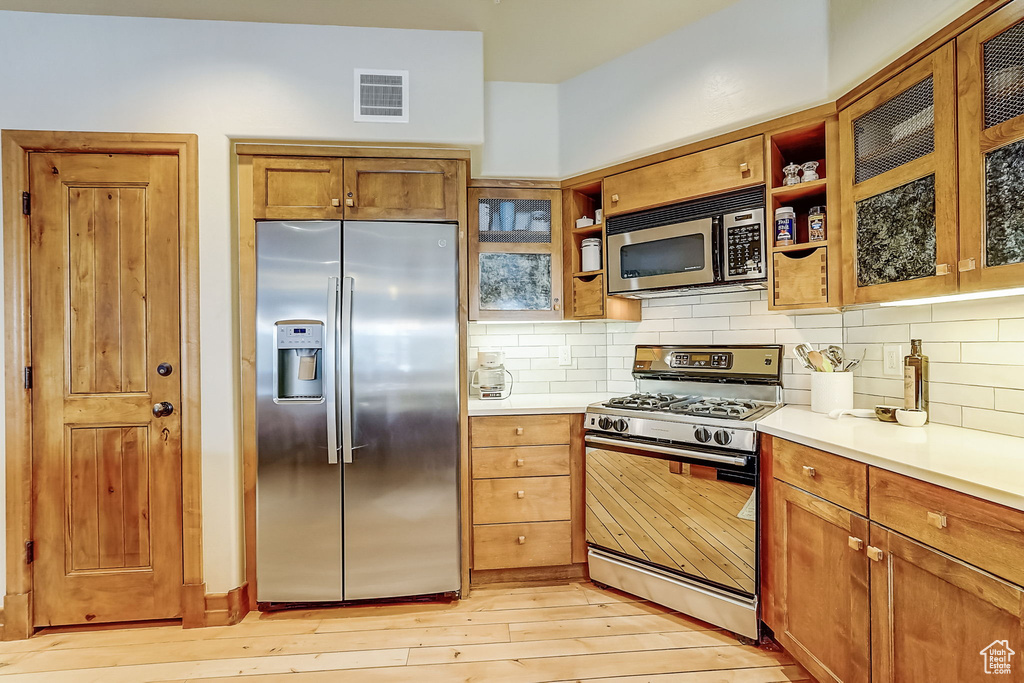 Kitchen with appliances with stainless steel finishes, backsplash, and light wood-type flooring