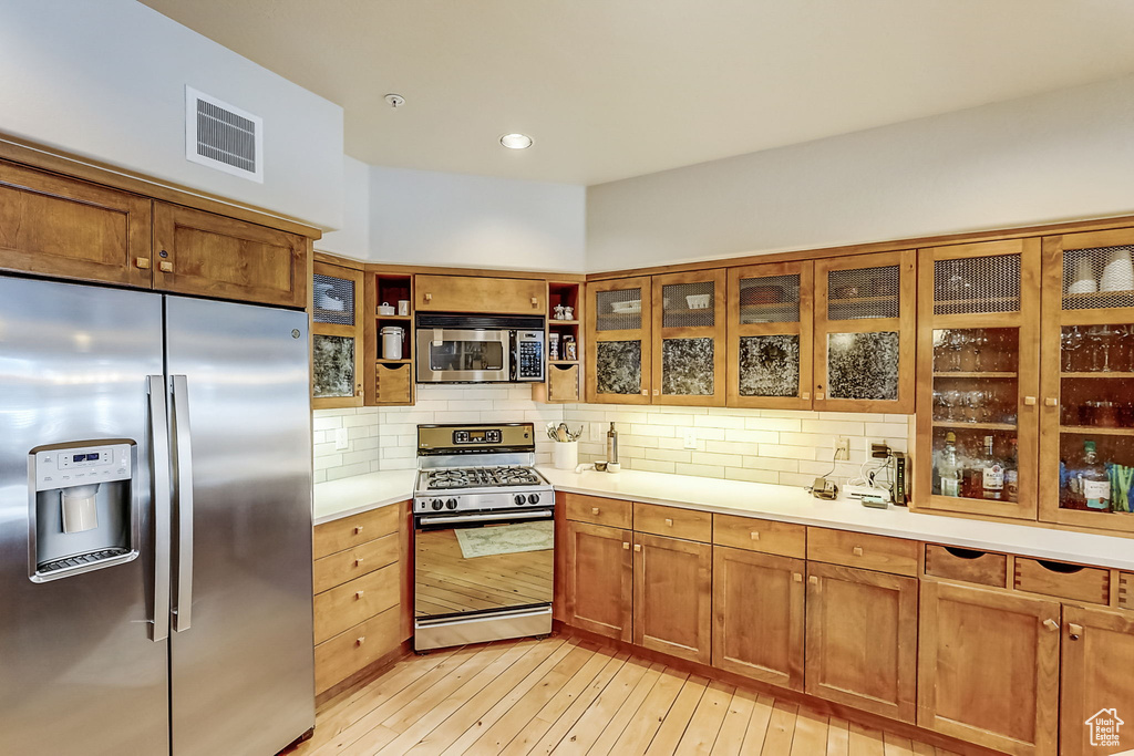 Kitchen featuring tasteful backsplash, stainless steel appliances, and light wood-type flooring