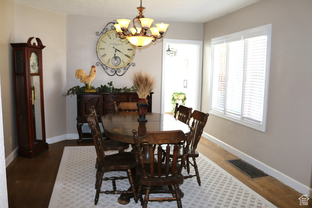 Dining area with dark hardwood / wood-style flooring, a chandelier, and a healthy amount of sunlight