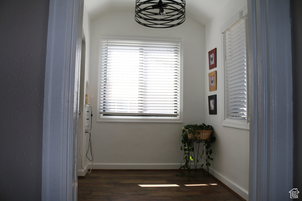 Hallway with dark hardwood / wood-style flooring and vaulted ceiling