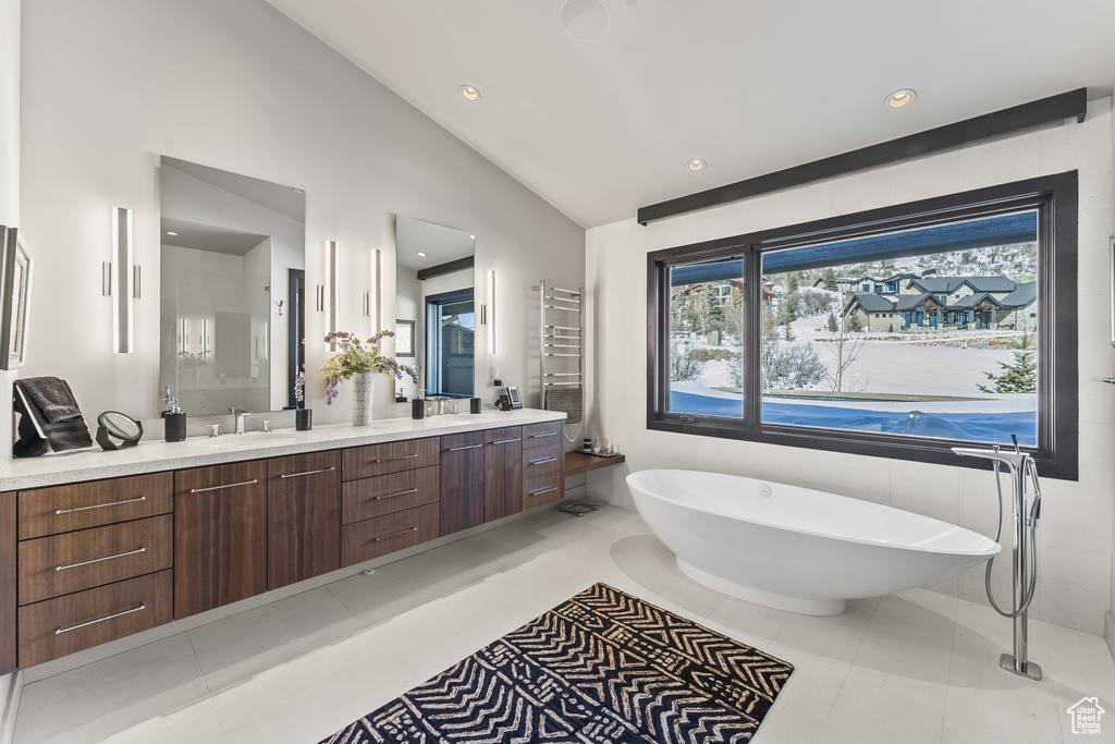 Bathroom with dual bowl vanity, tile floors, a bath, radiator, and vaulted ceiling