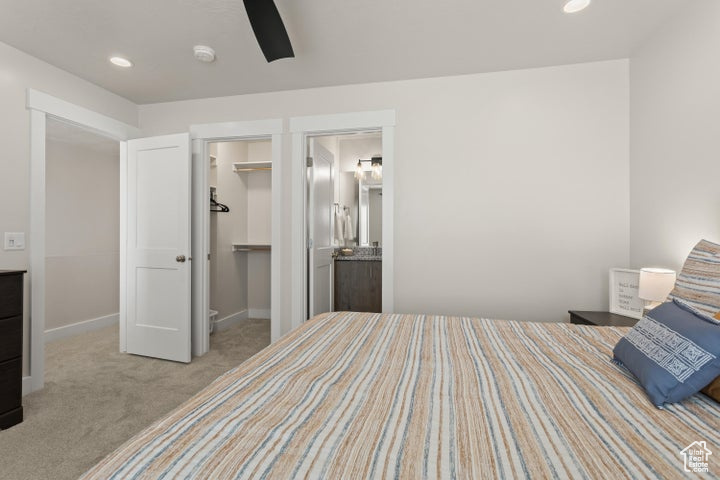 Carpeted bedroom featuring connected bathroom, a closet, a spacious closet, and ceiling fan