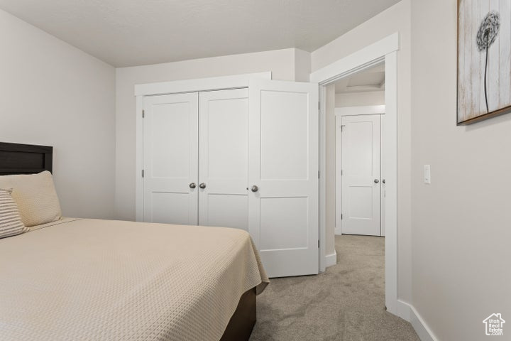 Bedroom with light carpet and a closet