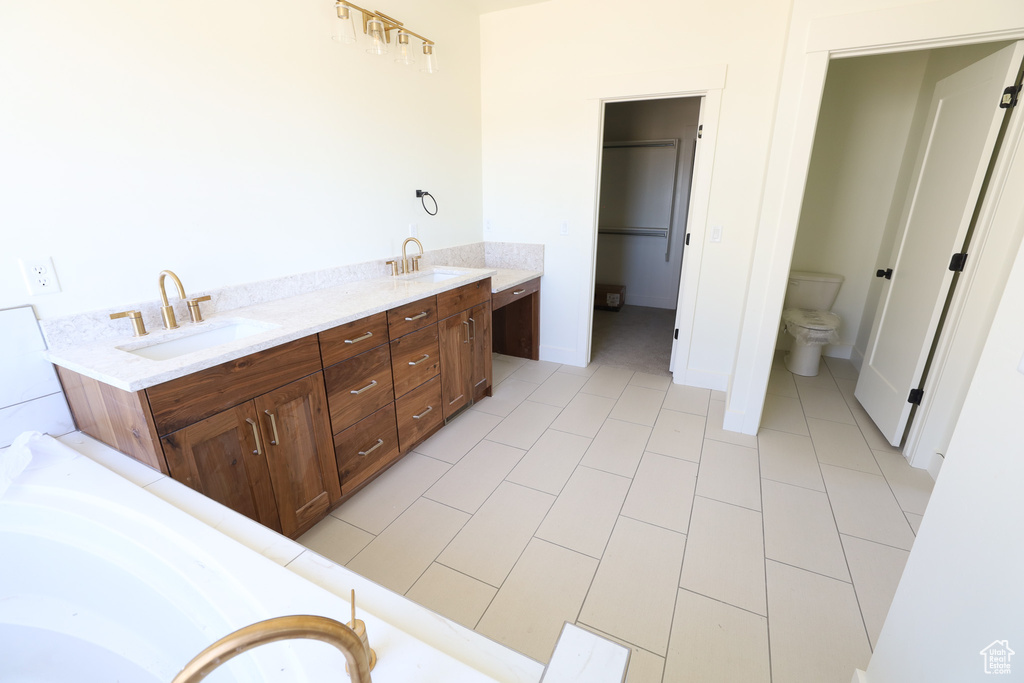 Bathroom with toilet, a bathing tub, dual bowl vanity, and tile flooring