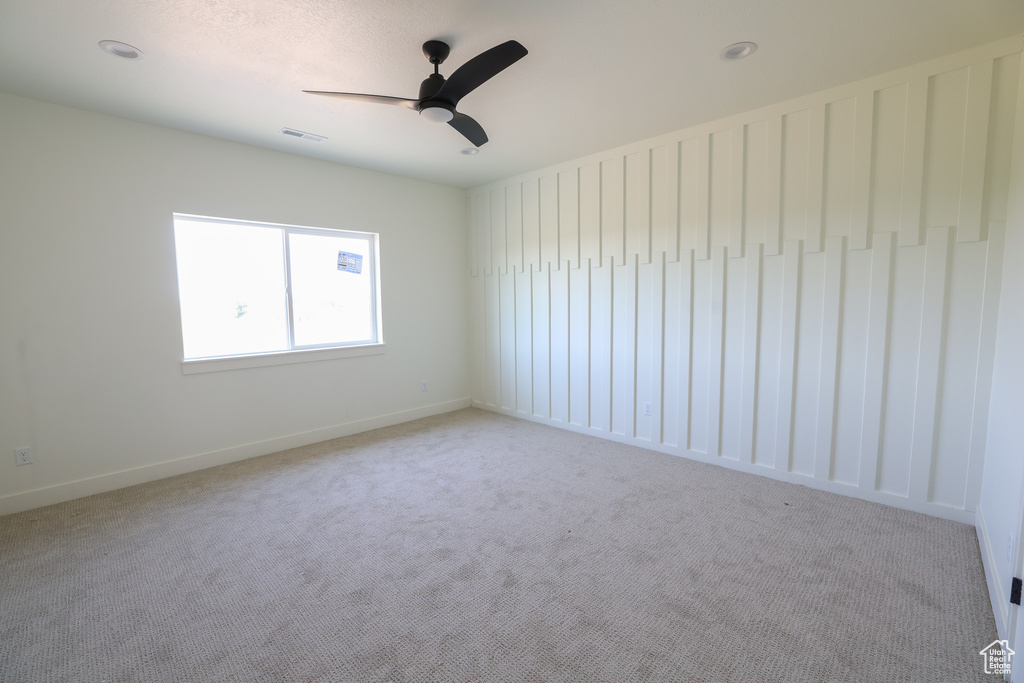Unfurnished room with ceiling fan and light colored carpet