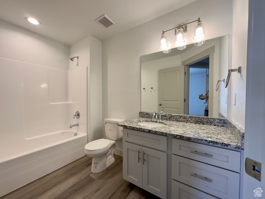 Full bathroom with large vanity, hardwood / wood-style floors, tub / shower combination, and toilet