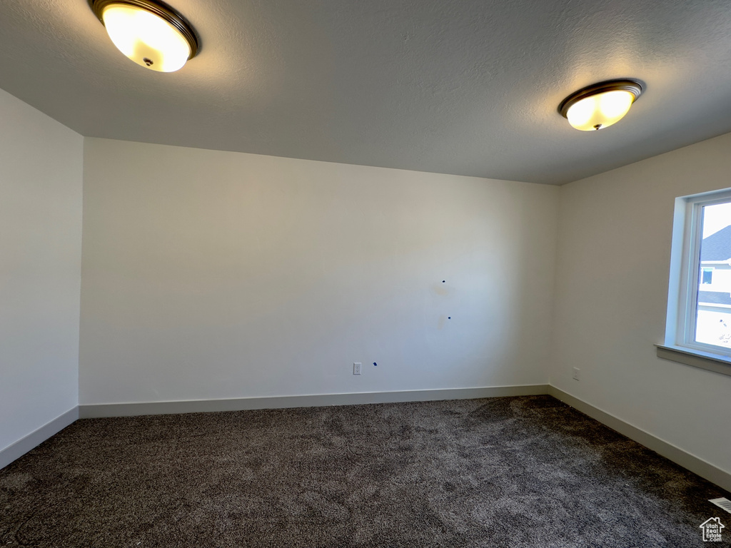 Unfurnished room featuring dark colored carpet