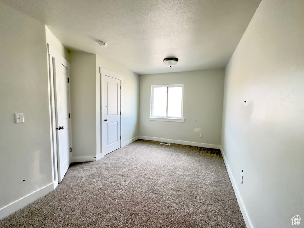 Unfurnished bedroom featuring light colored carpet and a textured ceiling
