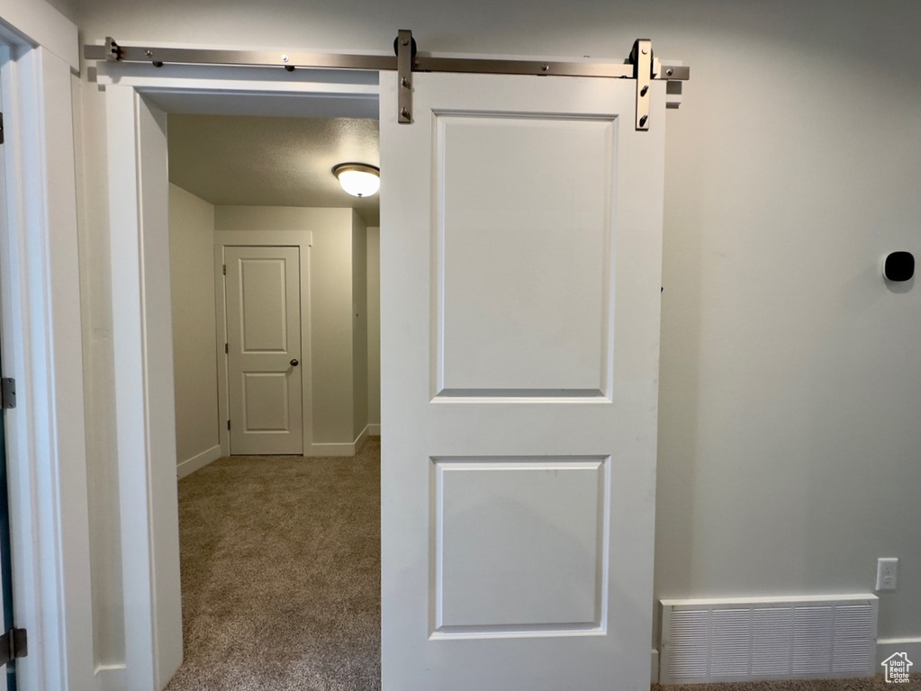 Corridor featuring light carpet and a barn door