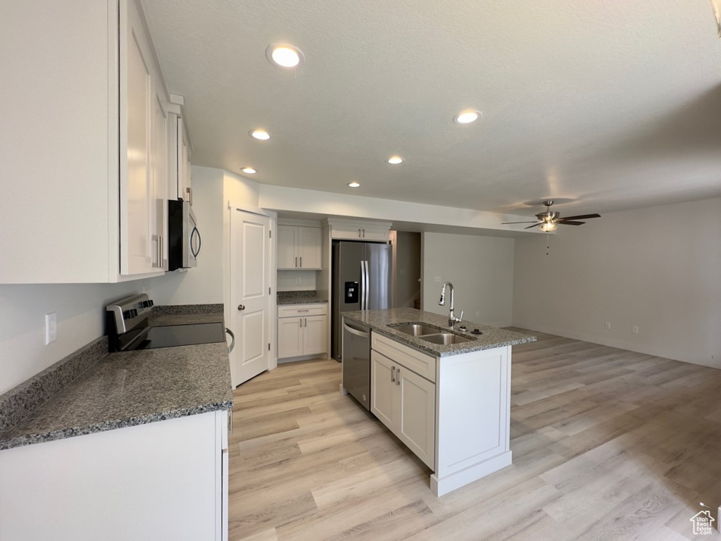 Kitchen with light wood-type flooring, ceiling fan, sink, an island with sink, and stainless steel appliances