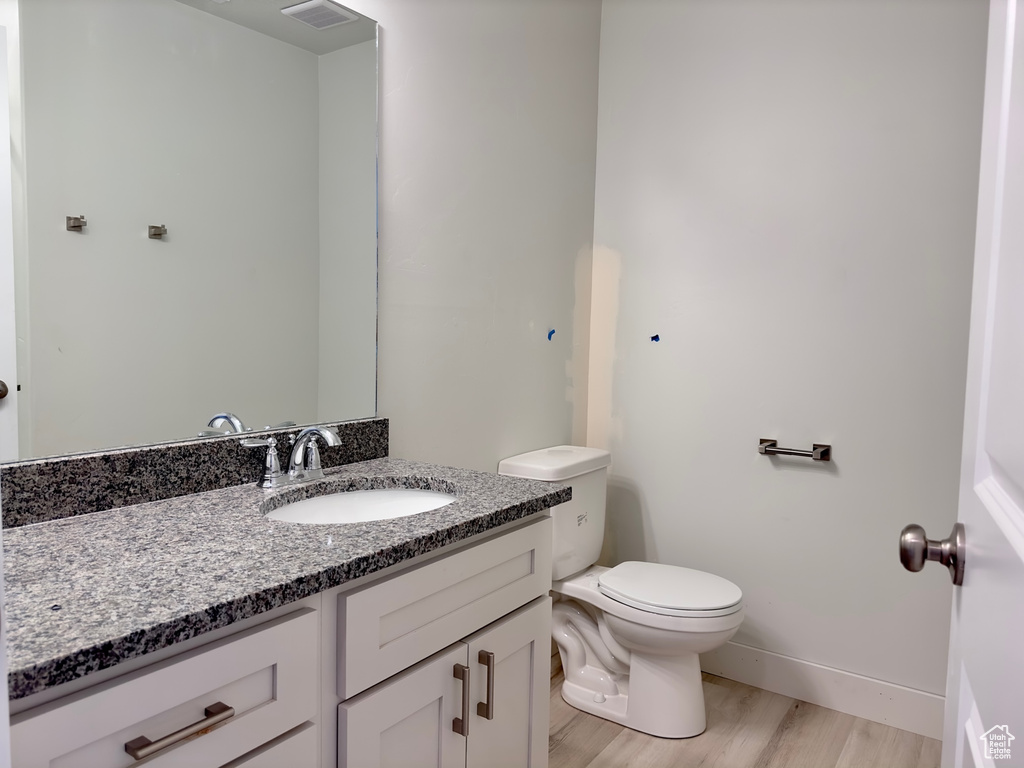 Bathroom with hardwood / wood-style floors, vanity, and toilet