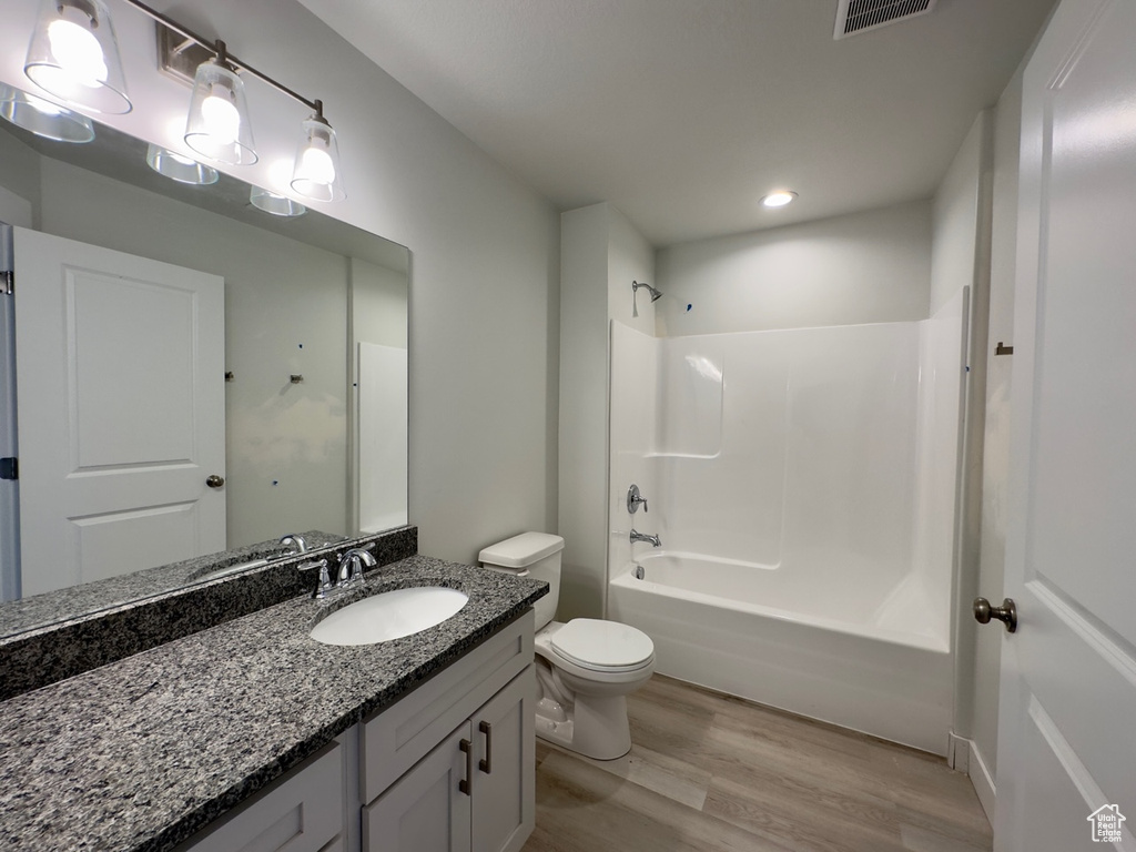 Full bathroom featuring large vanity, shower / bathing tub combination, hardwood / wood-style flooring, and toilet
