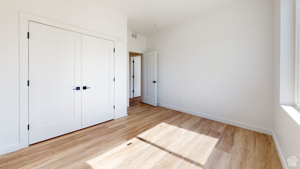 Unfurnished bedroom featuring light hardwood / wood-style floors and a closet