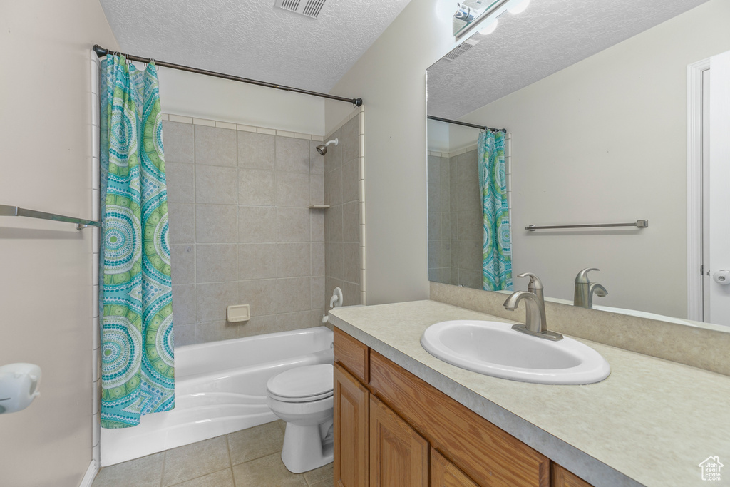Full bathroom with shower / bathtub combination with curtain, a textured ceiling, toilet, large vanity, and tile flooring