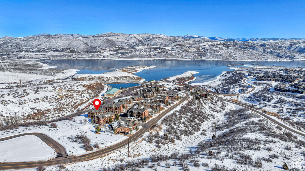 Snowy aerial view featuring a water and mountain view