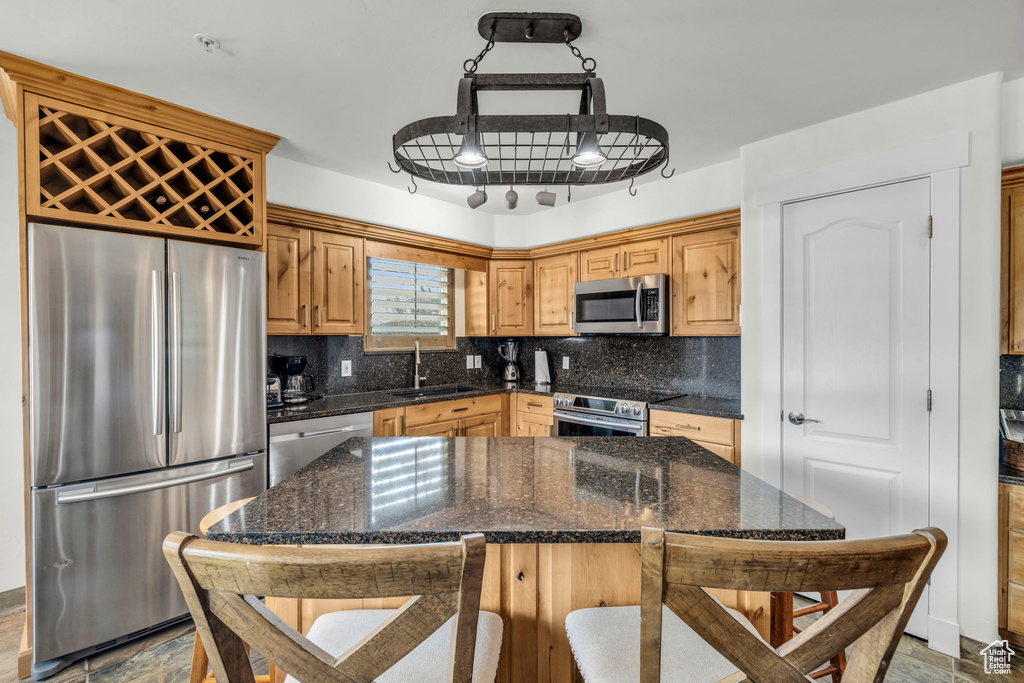 Kitchen featuring stainless steel appliances, dark stone counters, sink, and backsplash
