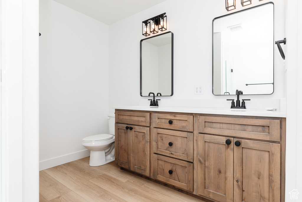Bathroom featuring double sink, oversized vanity, and wood-type flooring