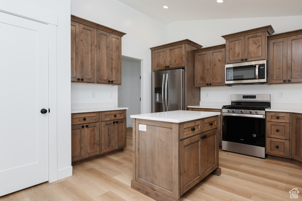 Kitchen featuring light hardwood / wood-style floors, a kitchen island, dark brown cabinets, vaulted ceiling, and stainless steel appliances