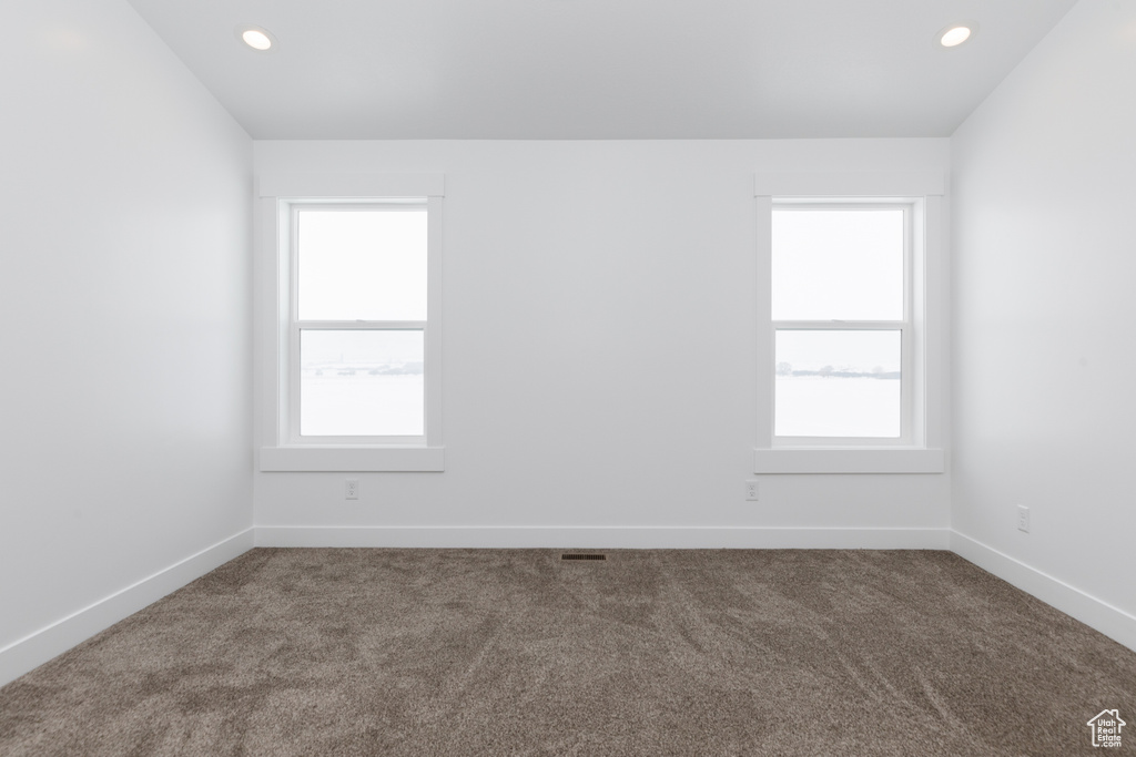 Unfurnished room with dark colored carpet and a healthy amount of sunlight