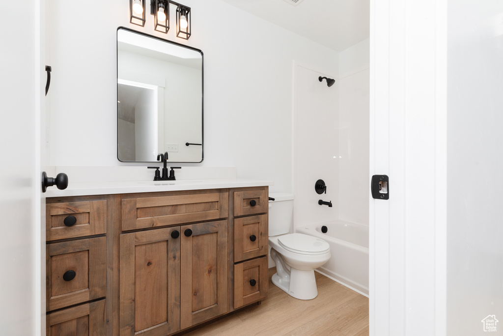 Full bathroom with large vanity, hardwood / wood-style flooring, shower / bathing tub combination, and toilet