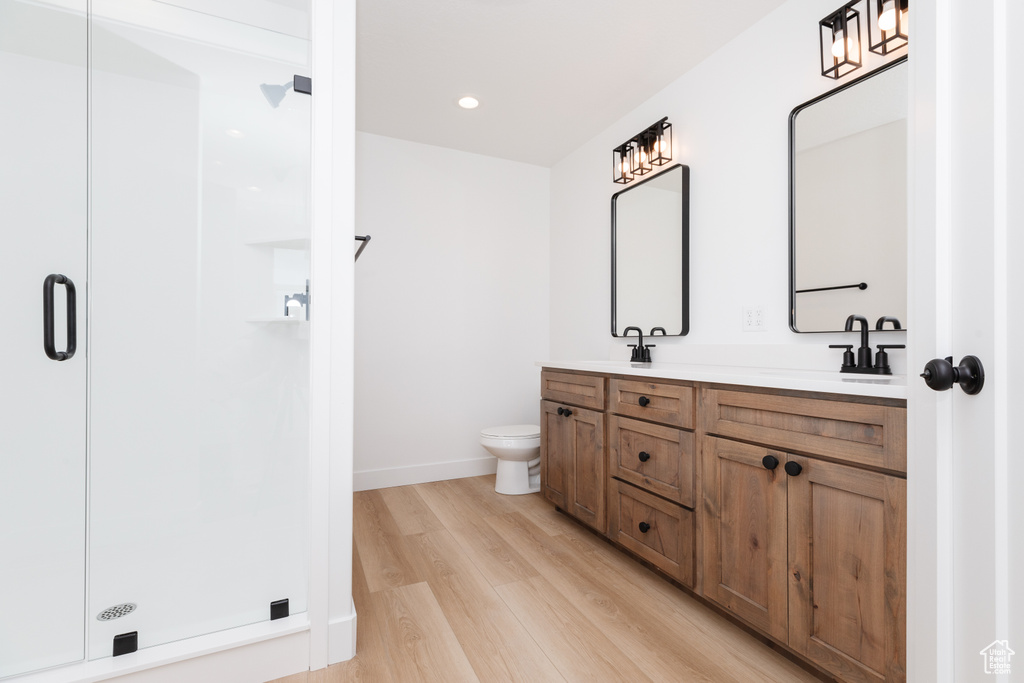 Bathroom with toilet, a shower with door, hardwood / wood-style flooring, and dual bowl vanity