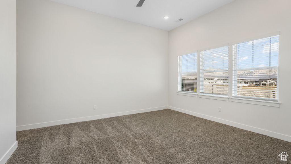 Empty room featuring dark carpet and ceiling fan