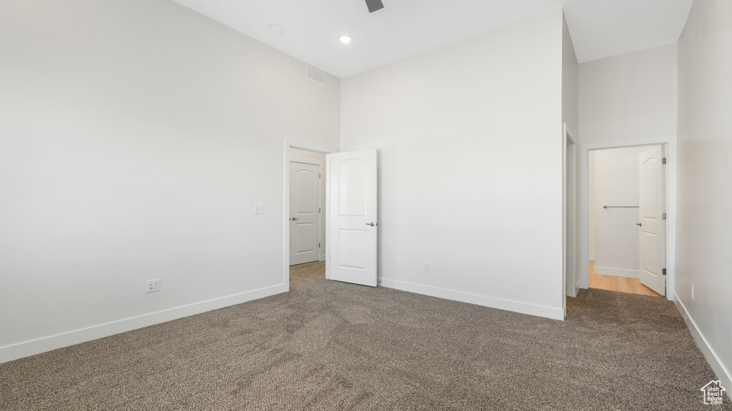 Unfurnished bedroom featuring carpet, ceiling fan, and high vaulted ceiling