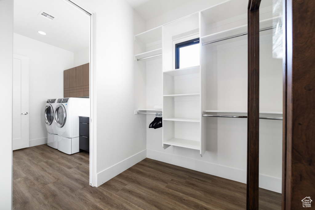 Spacious closet with dark hardwood / wood-style floors and washer and clothes dryer