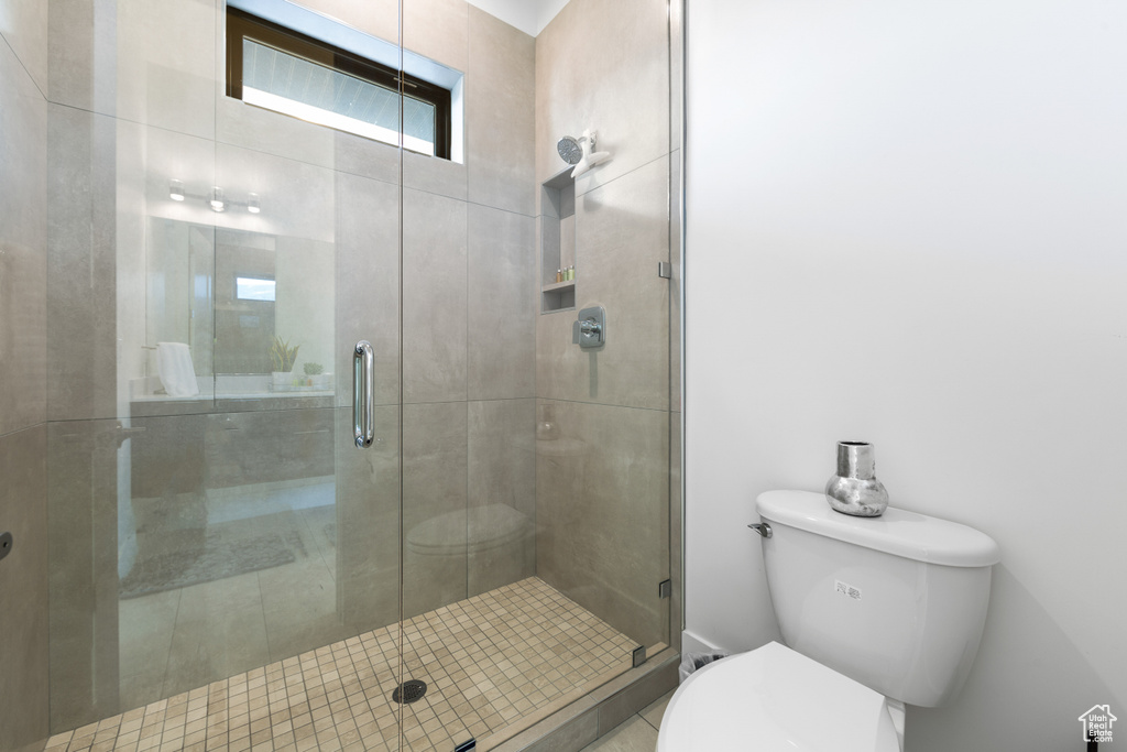 Bathroom featuring toilet and a shower with shower door
