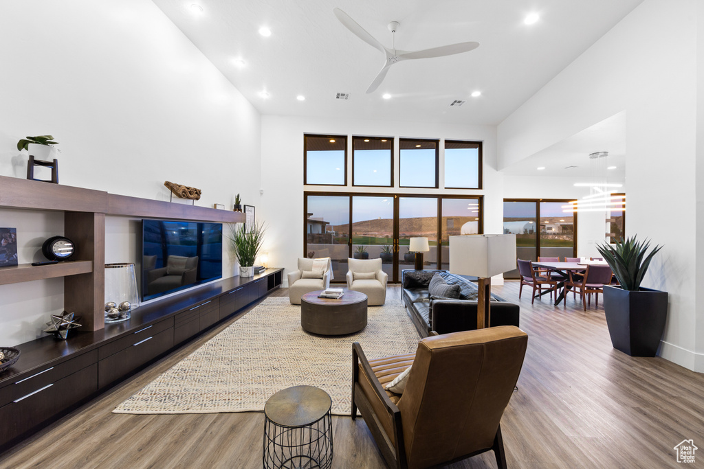 Living room with light hardwood / wood-style flooring, ceiling fan, and a towering ceiling