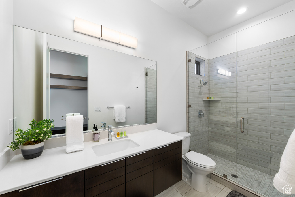 Bathroom featuring walk in shower, toilet, tile flooring, and large vanity