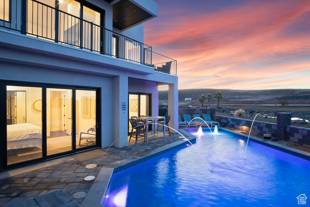 Pool at dusk with a patio and pool water feature