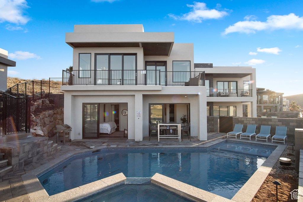 Back of property with a patio, a pool with hot tub, and a balcony