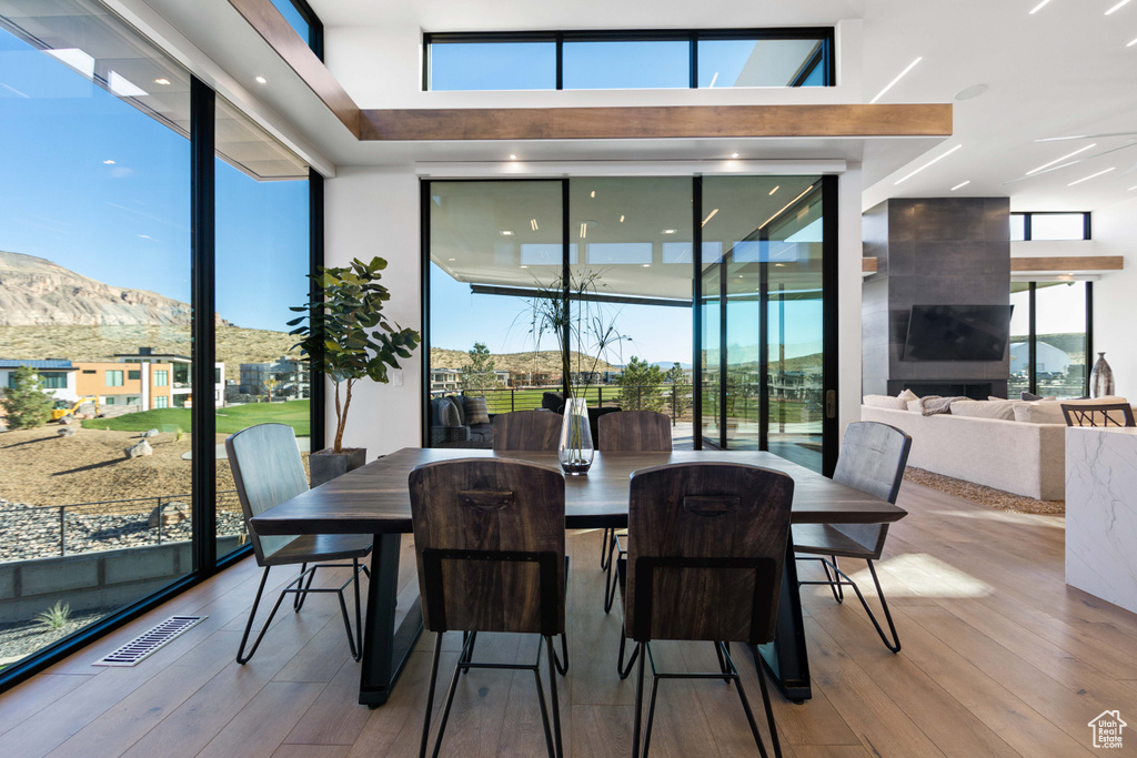 Dining room with a mountain view, light hardwood / wood-style flooring, and a towering ceiling