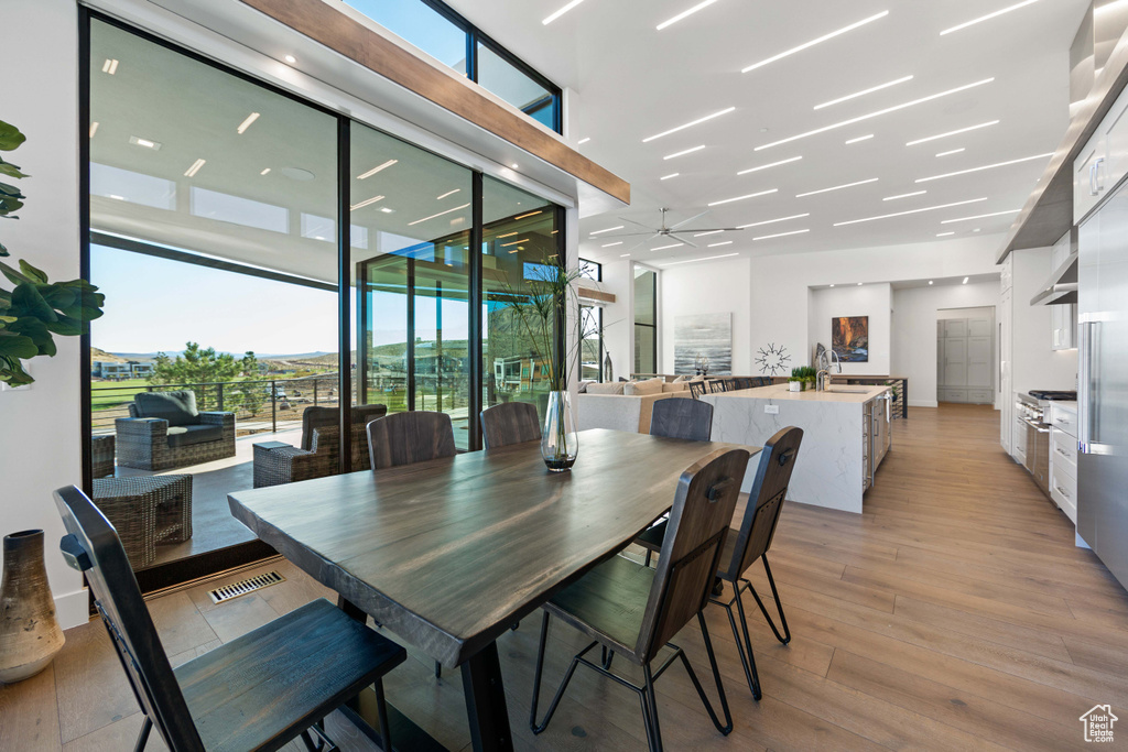 Dining area featuring sink, ceiling fan, light hardwood / wood-style floors, and expansive windows