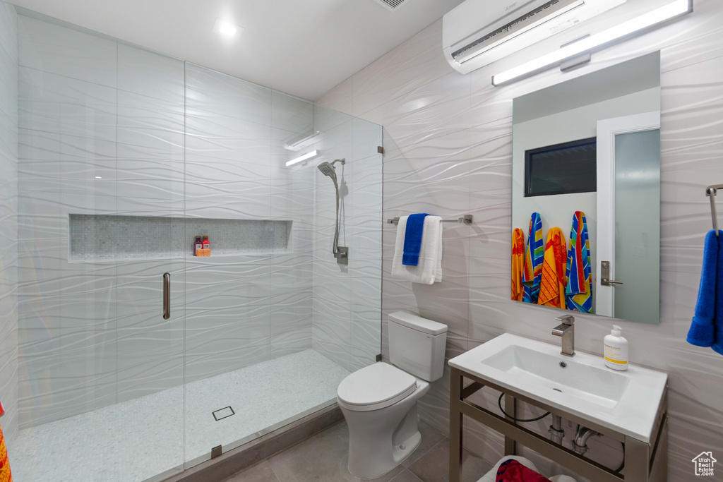 Bathroom featuring a shower with shower door, toilet, tile flooring, and tile walls