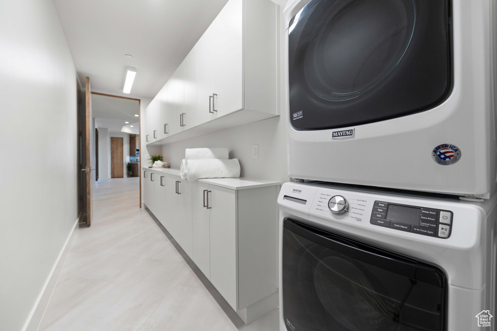 Laundry room with stacked washing maching and dryer and cabinets