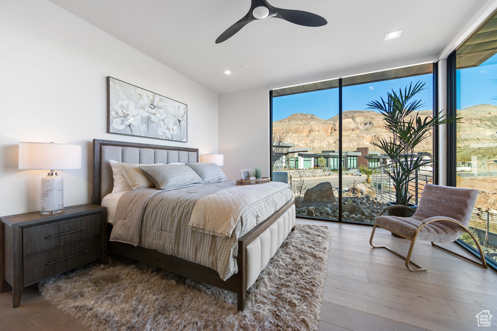 Bedroom with ceiling fan, a mountain view, access to exterior, expansive windows, and wood-type flooring