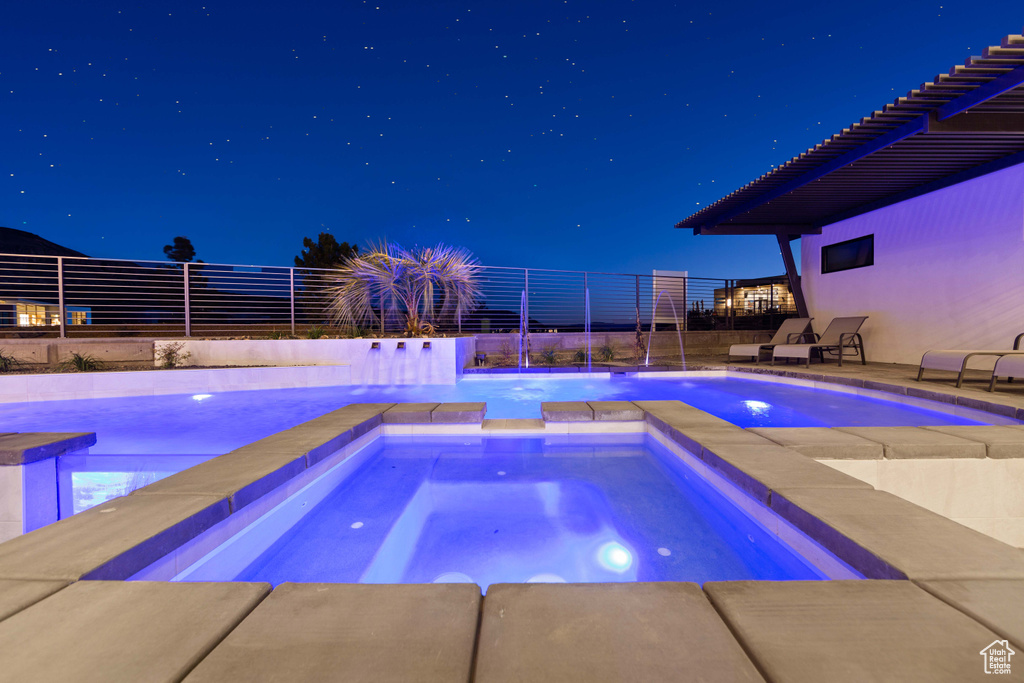 Pool at night featuring a patio area