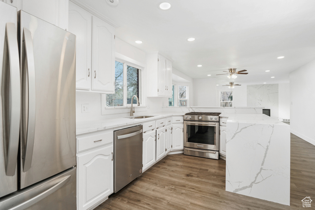 Kitchen with sink, stainless steel appliances, white cabinets, and hardwood / wood-style flooring