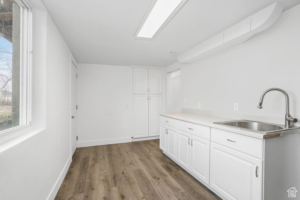 Kitchen with wood-type flooring, sink, and white cabinetry