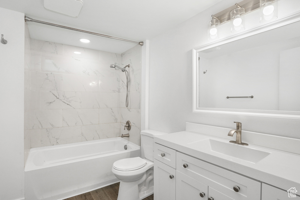 Full bathroom featuring hardwood / wood-style floors, tiled shower / bath combo, toilet, and vanity