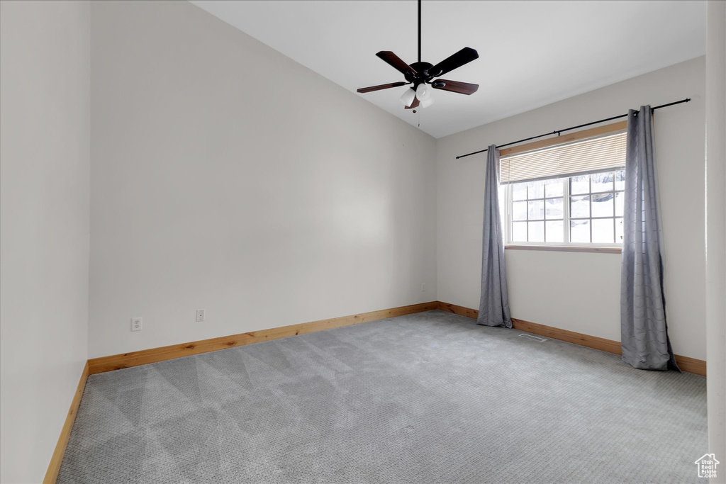 Empty room with lofted ceiling, ceiling fan, and light carpet