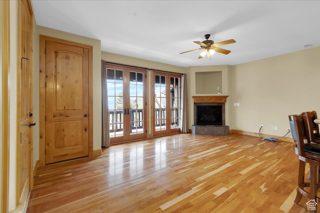 Unfurnished living room featuring light wood-type flooring, ceiling fan, and french doors
