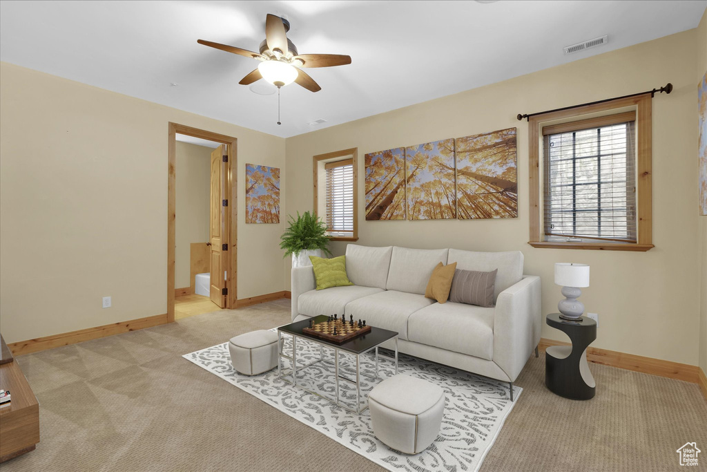 Living room with ceiling fan, light colored carpet, and a healthy amount of sunlight