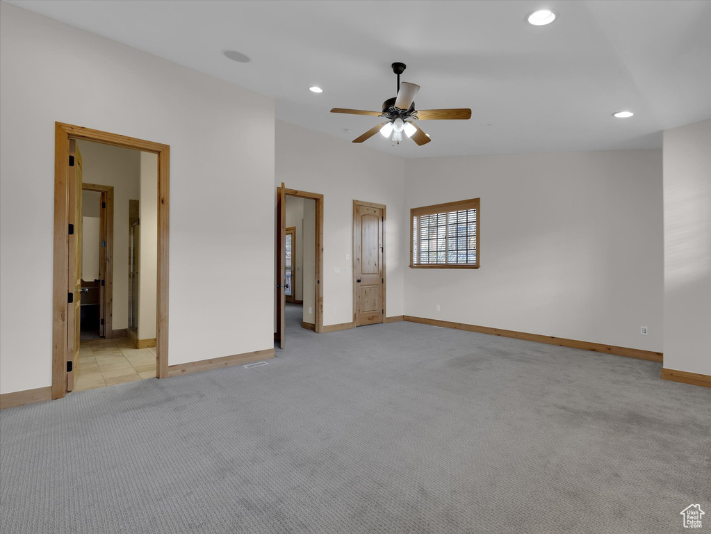Unfurnished bedroom featuring light colored carpet, lofted ceiling, ceiling fan, and connected bathroom