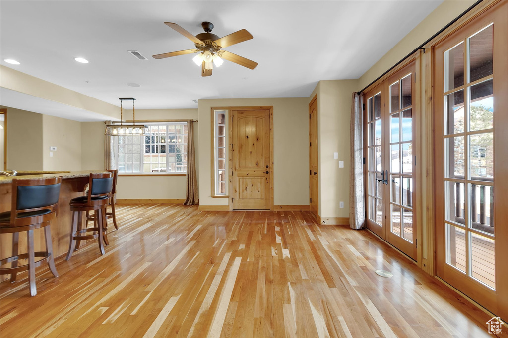 Interior space with a healthy amount of sunlight, light hardwood / wood-style flooring, and ceiling fan with notable chandelier